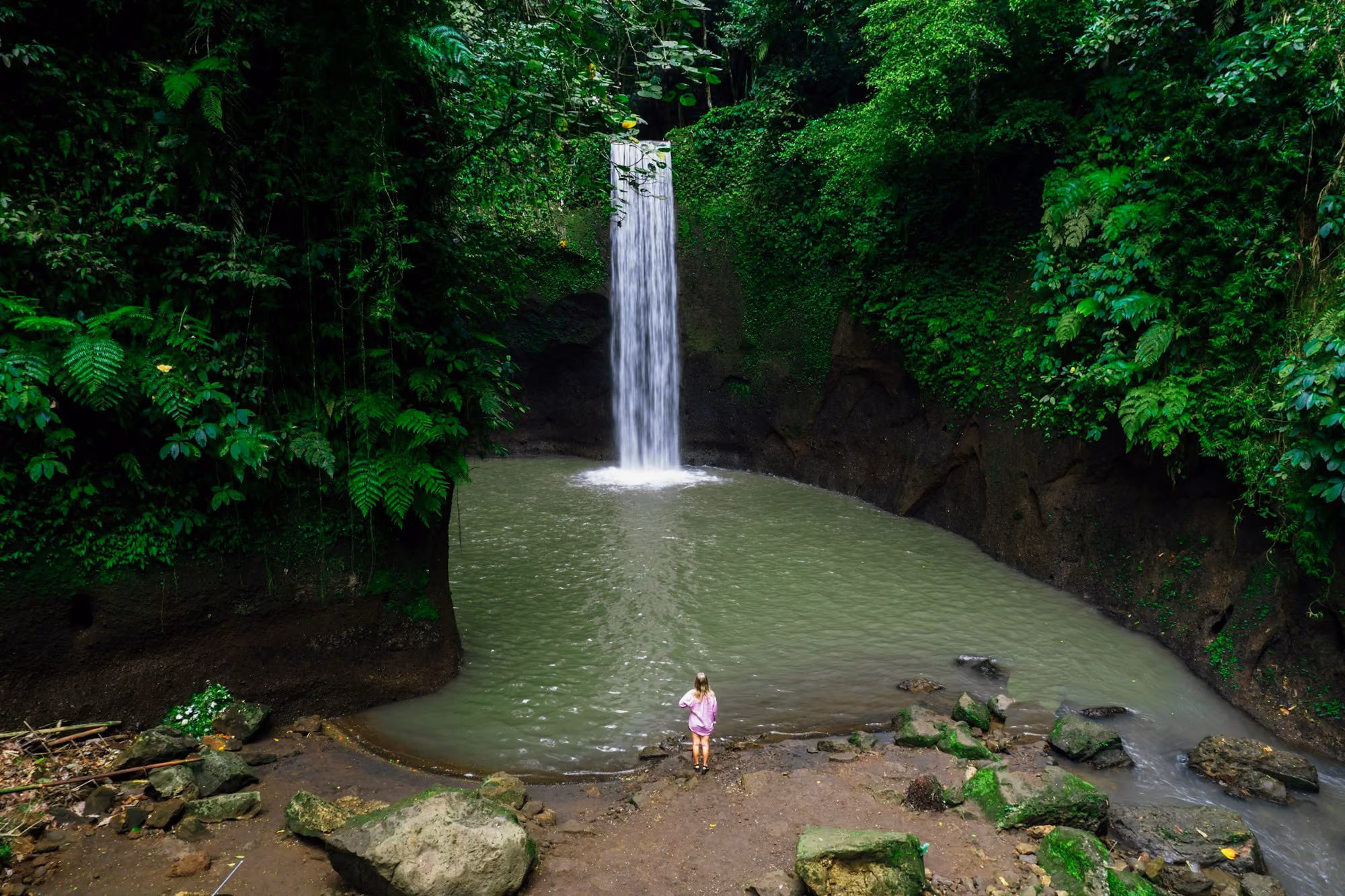 Near COMO Shambhala Estate: A person standing in front of a waterfall