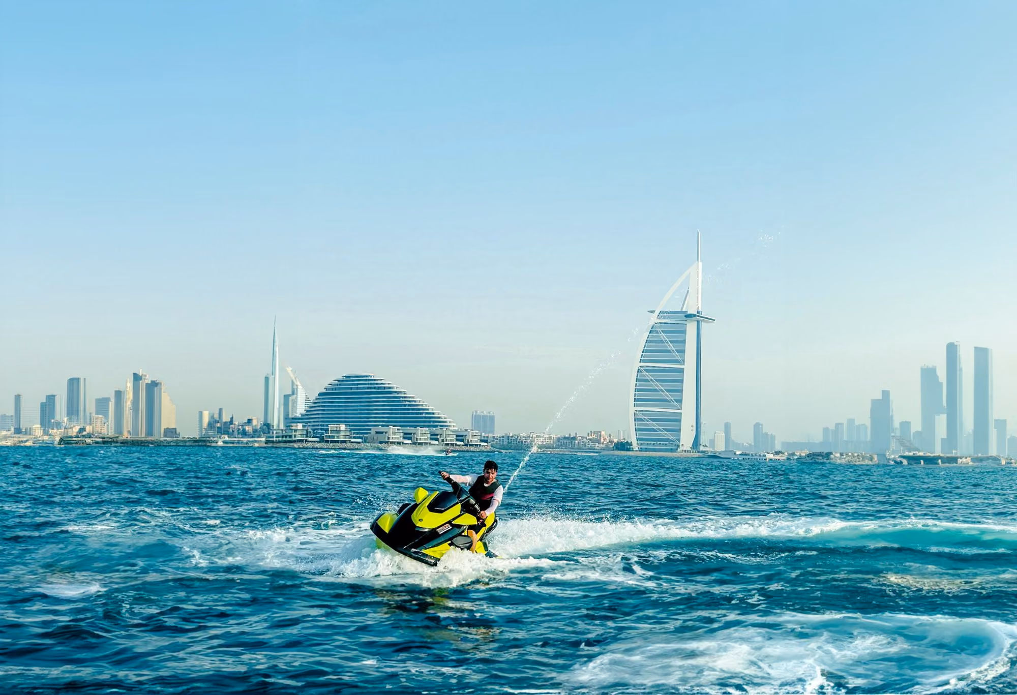 Near Four Seasons Resort Dubai at Jumeirah Beach: a man riding a jet ski on top of a body of water