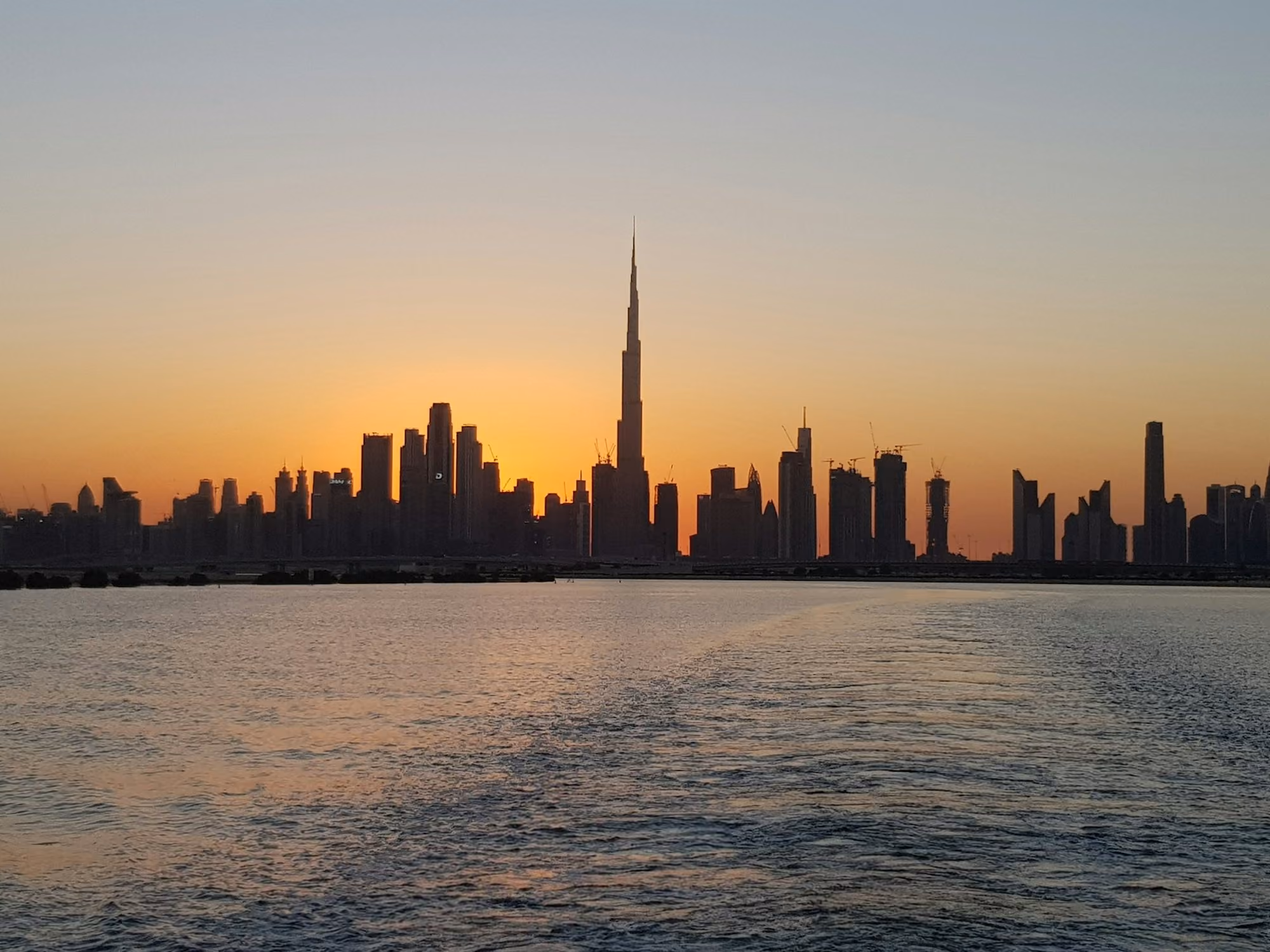 Near Waldorf Astoria Dubai Palm Jumeirah: city skyline across body of water during sunset