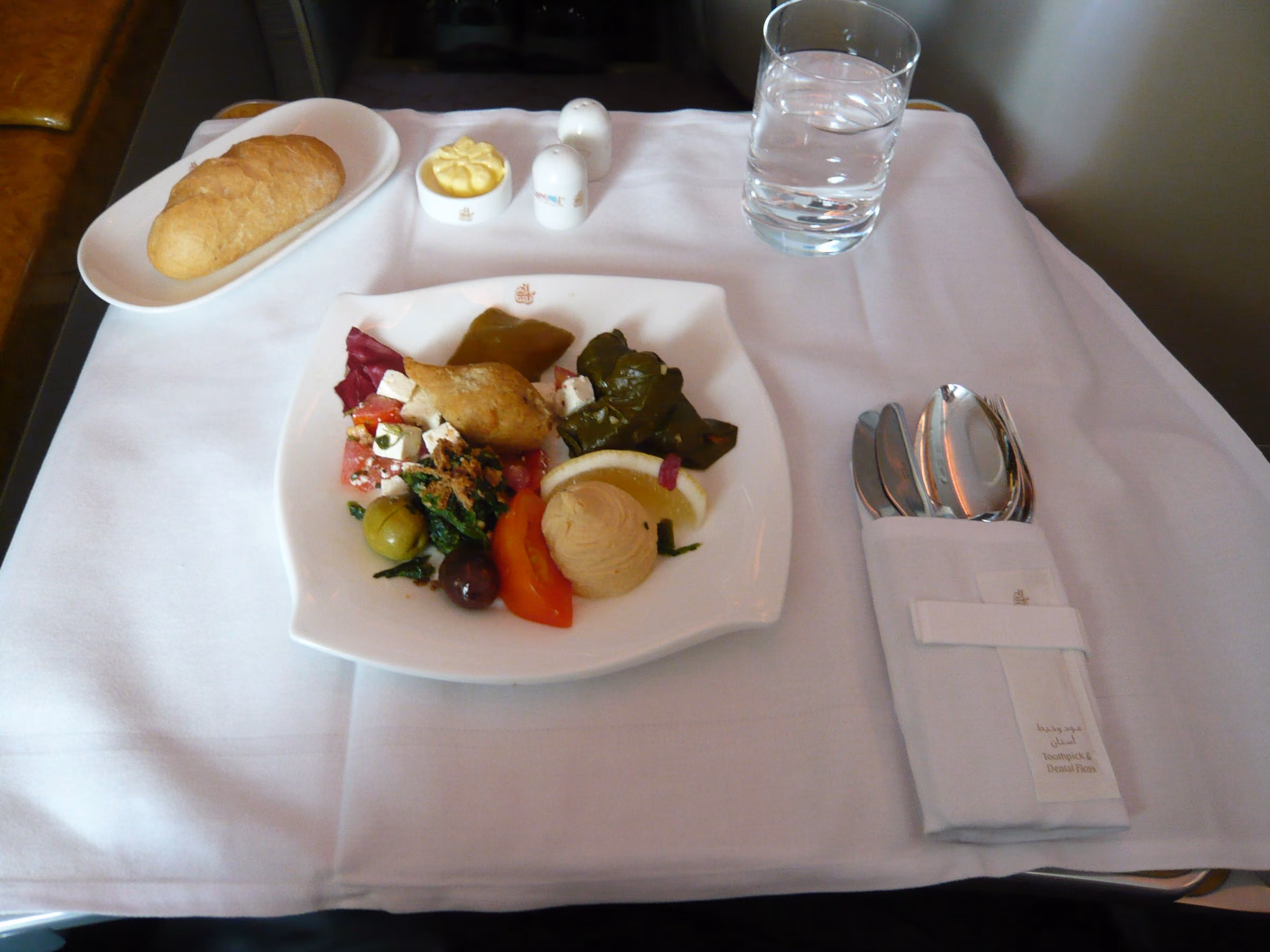 Arabic mezze, bread and water laid on a white tablecloth at an Emirates A380 business class seat