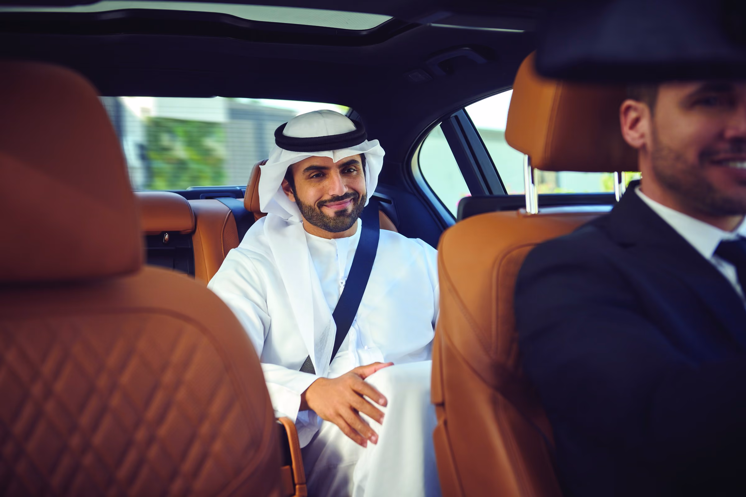 A passenger in the back of an Emirates Chauffeur-drive car, talking to the driver