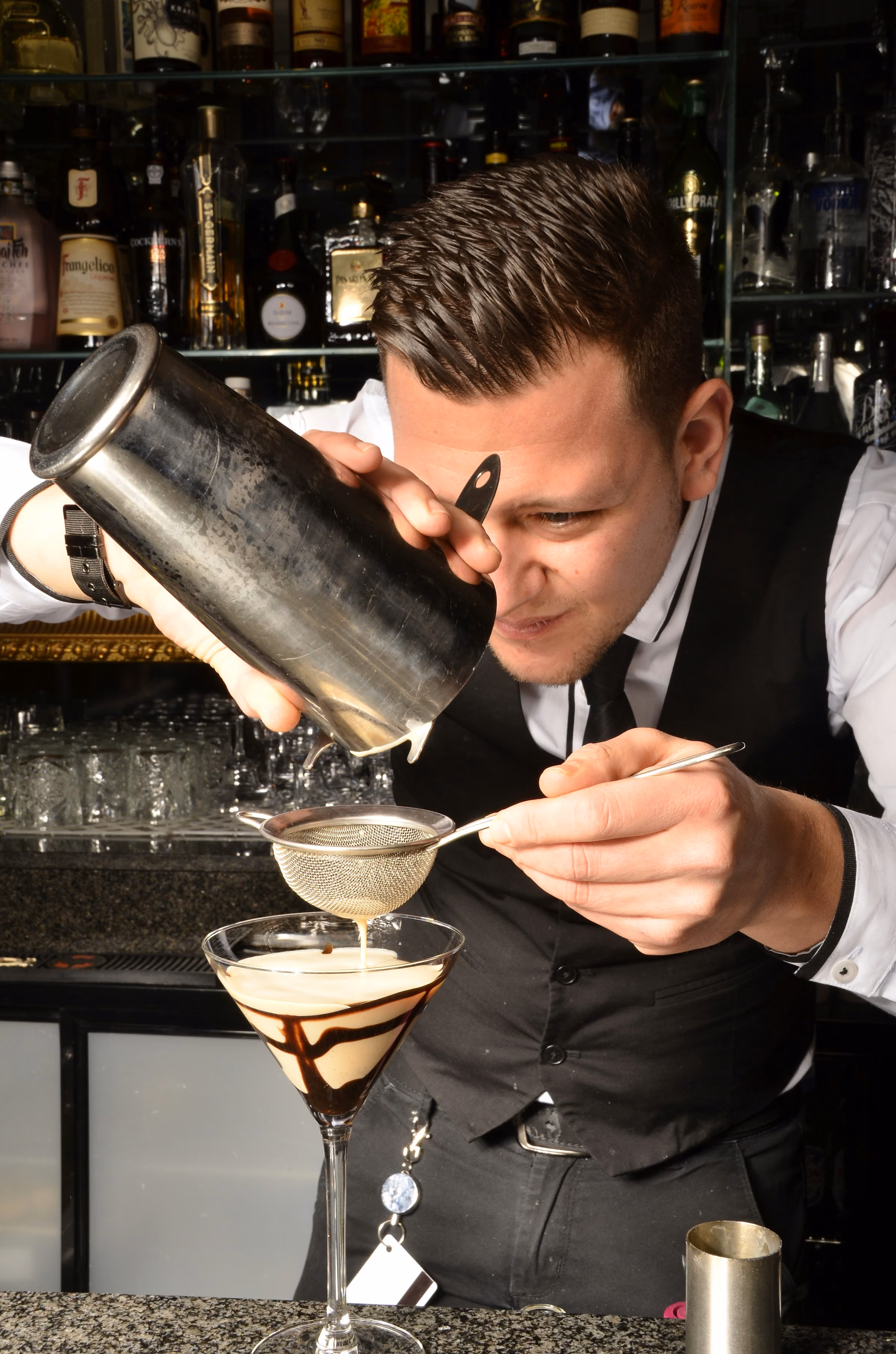 A bartender straining a cocktail