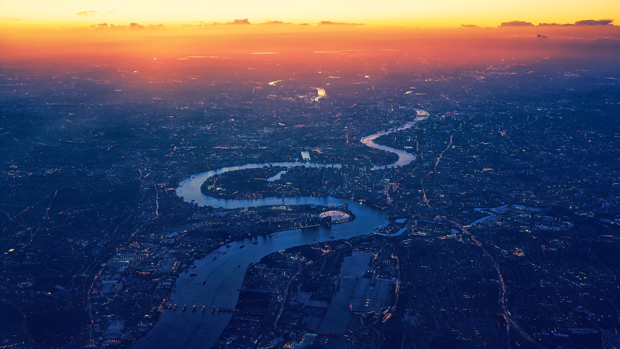 The curve of the Thames through London at dusk from above
