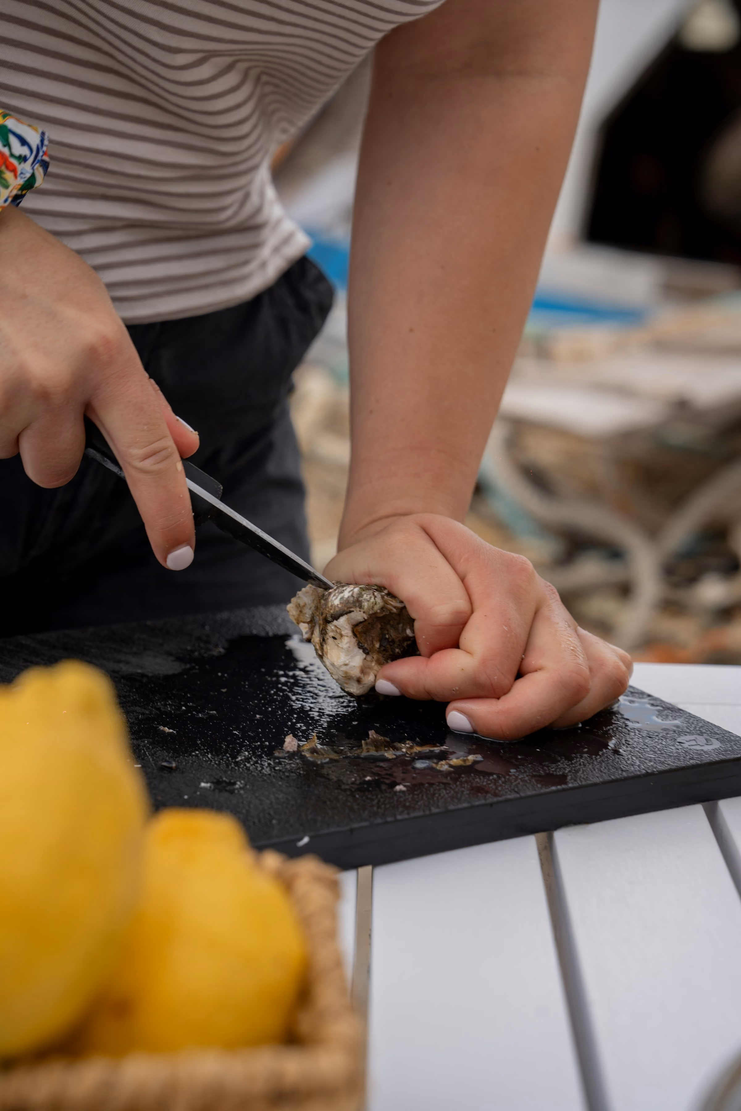 Hands opening an oyster with a knife