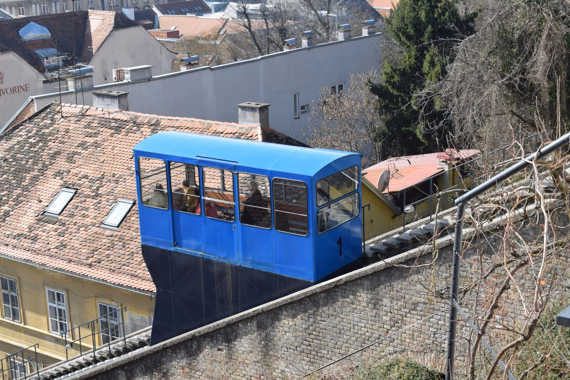 Near Esplanade Zagreb Hotel: a blue train traveling down tracks next to tall buildings