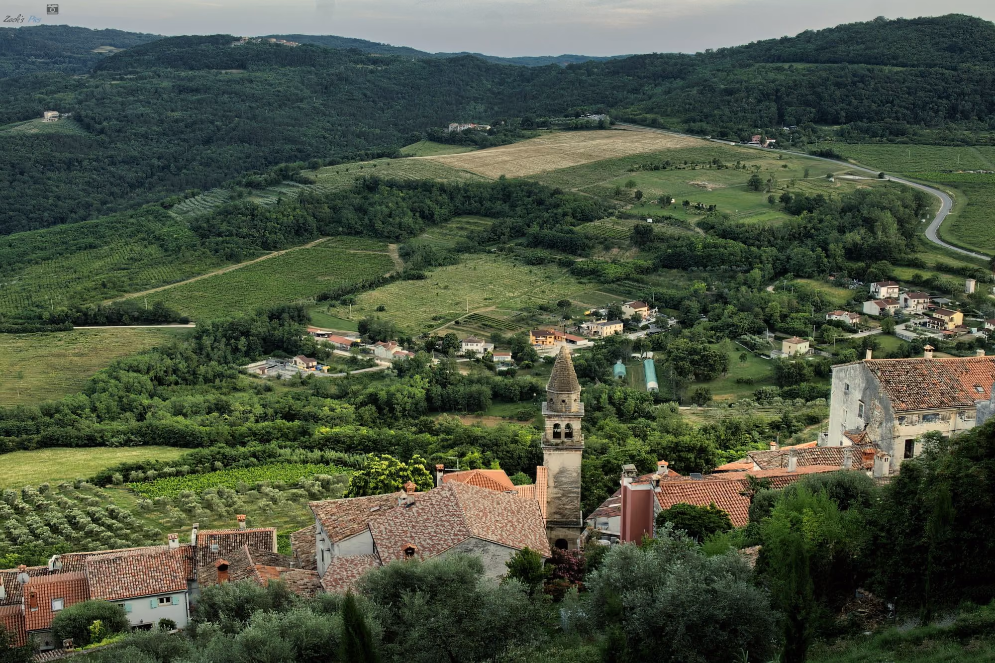 Near Meneghetti Wine Hotel & Winery: Historic village with a bell tower surrounded by green hills