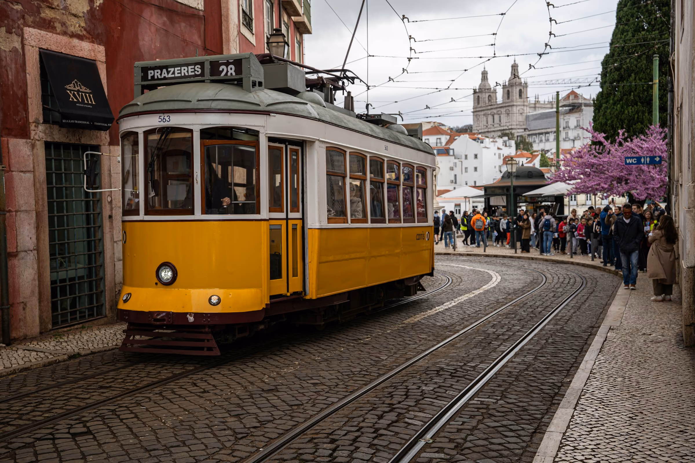 A yellow tram climbing a narrow cobbled street in Lisbon