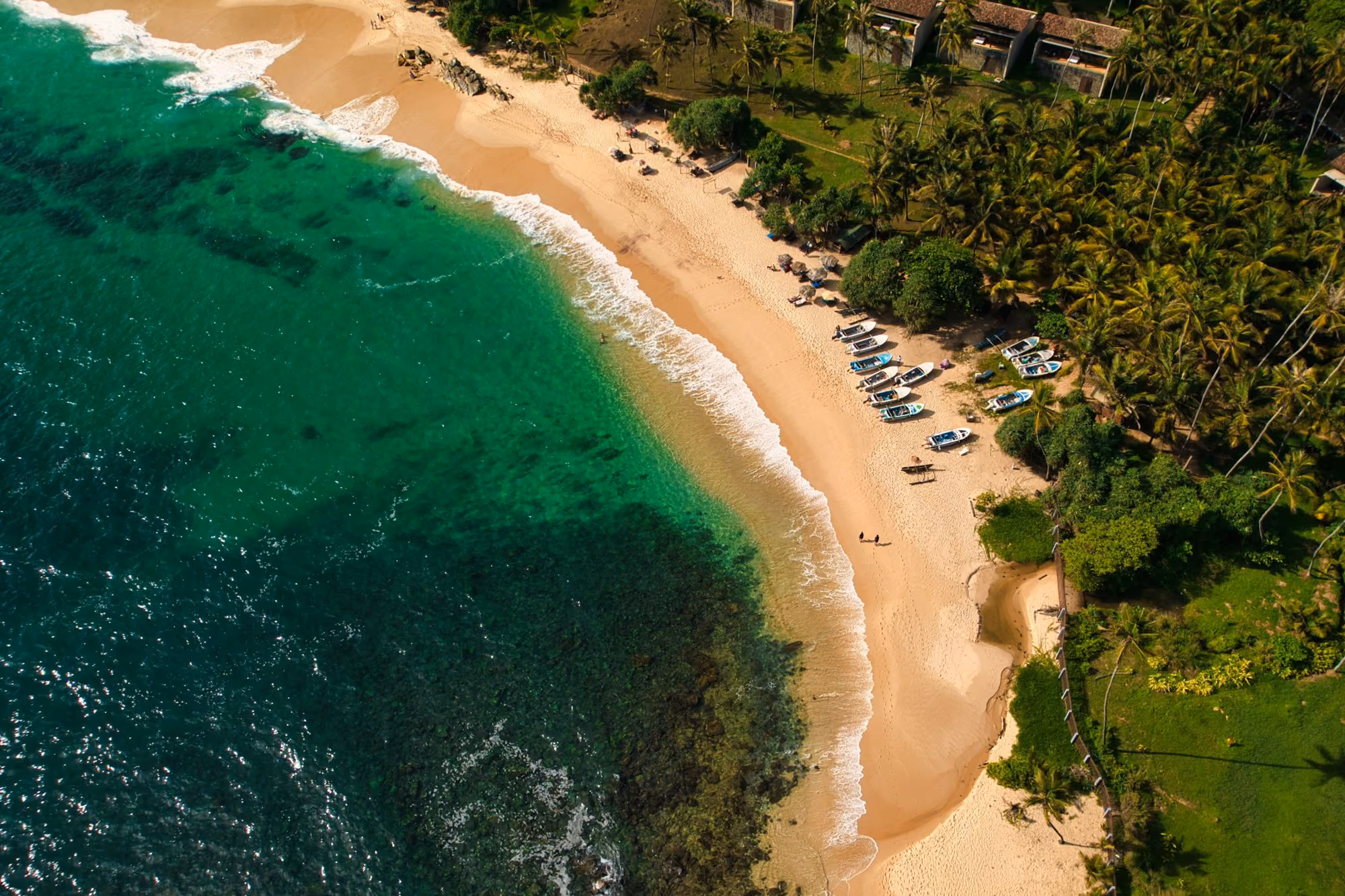 Near Kayaam House: An aerial view of a sandy beach with small boats and palm trees