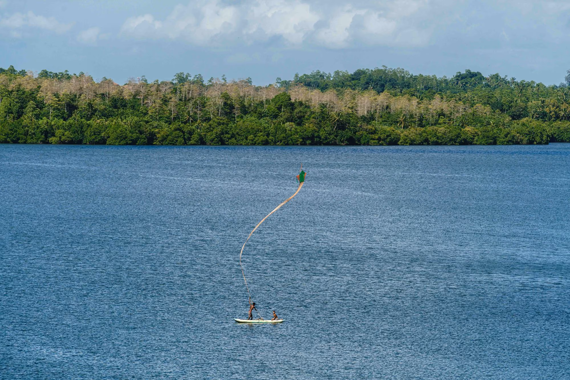 Near Kurulu Bay: a person is parasailing on a lake with trees in the background