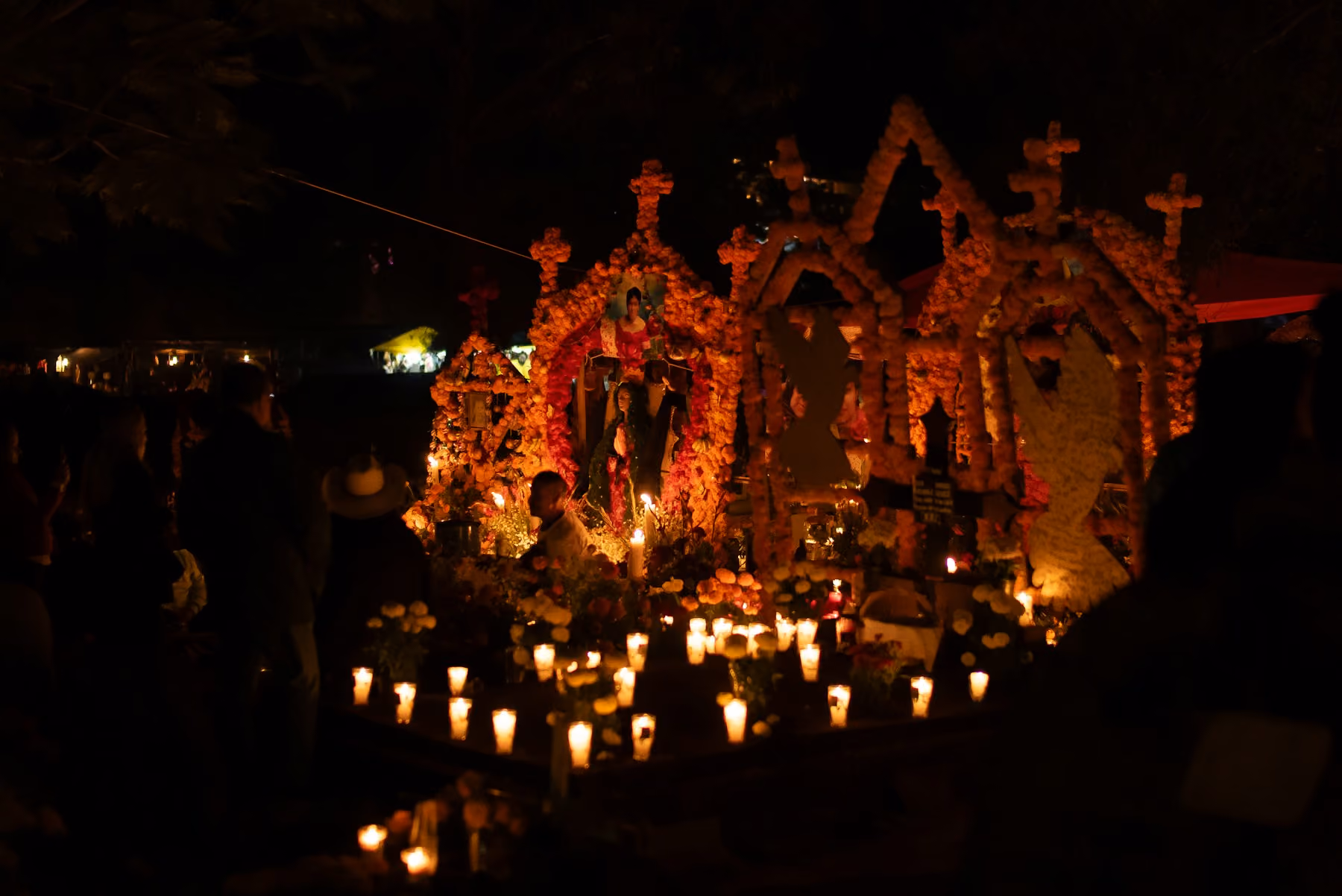Marigold arches and rows of candles on a family grave on the Night of the Dead in Mexico