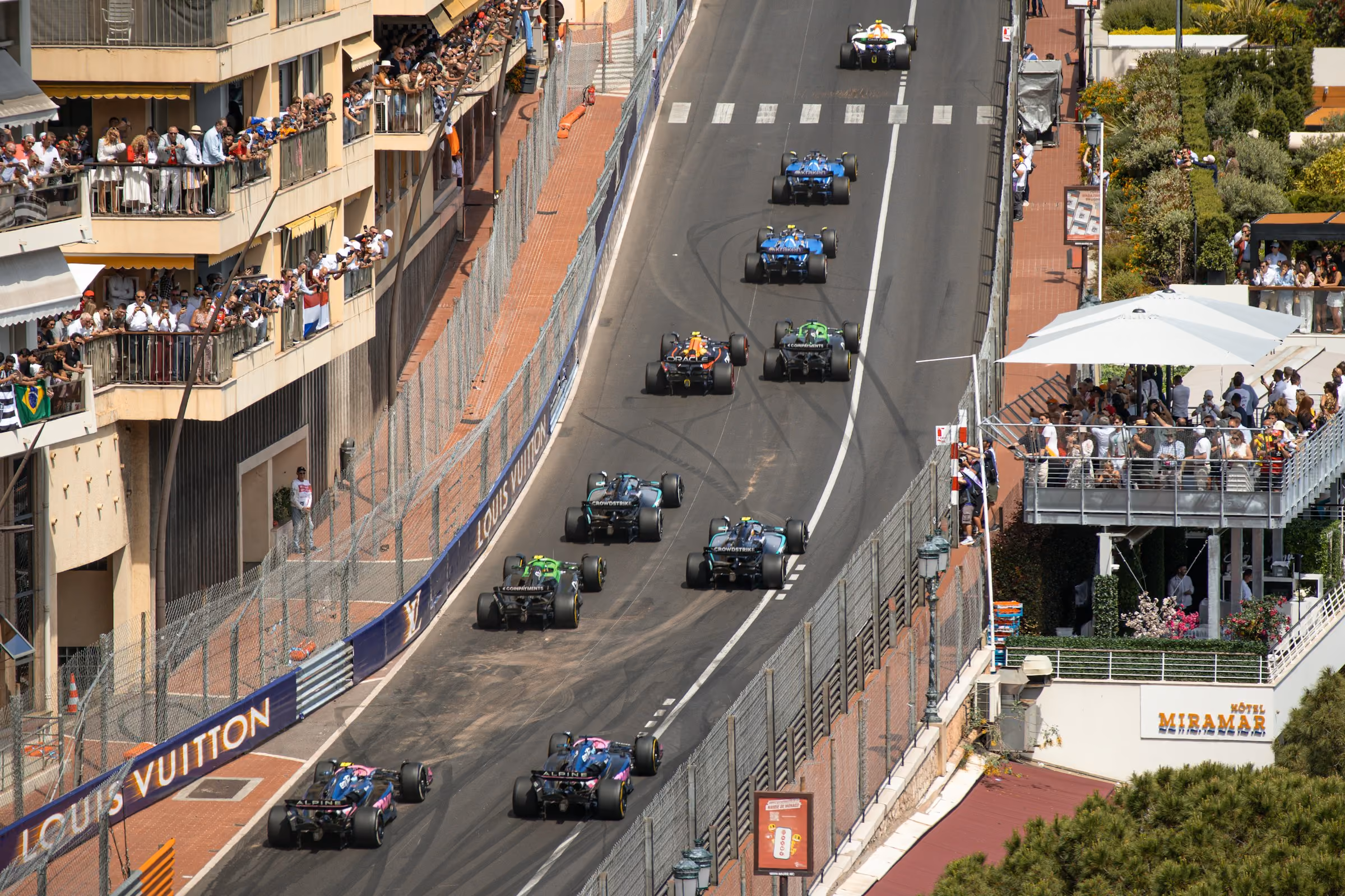 Formula 1 cars racing along the Monaco street circuit past packed balconies
