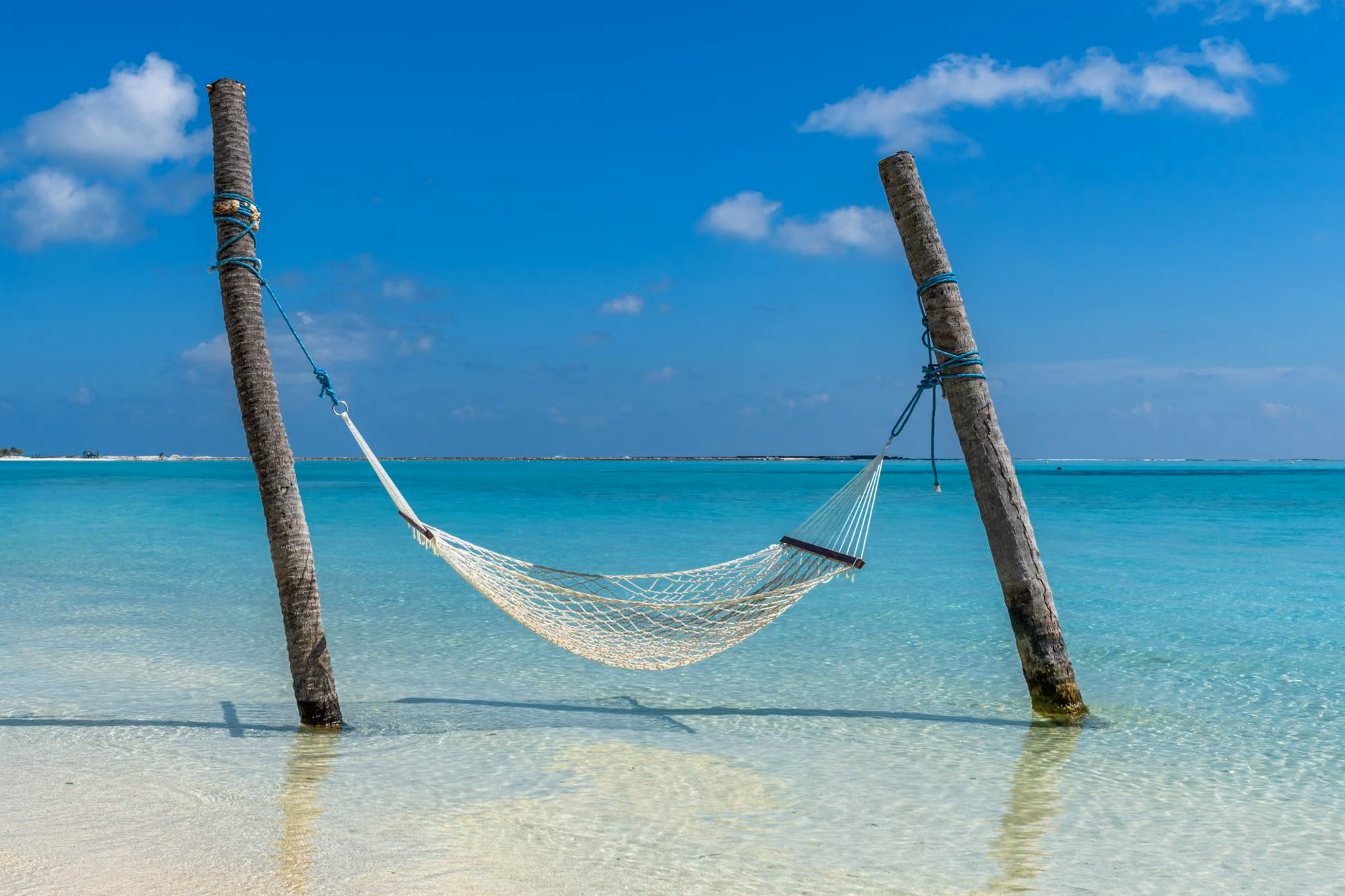 Near JOALI BEING: a hammock hanging between two wooden poles in the ocean