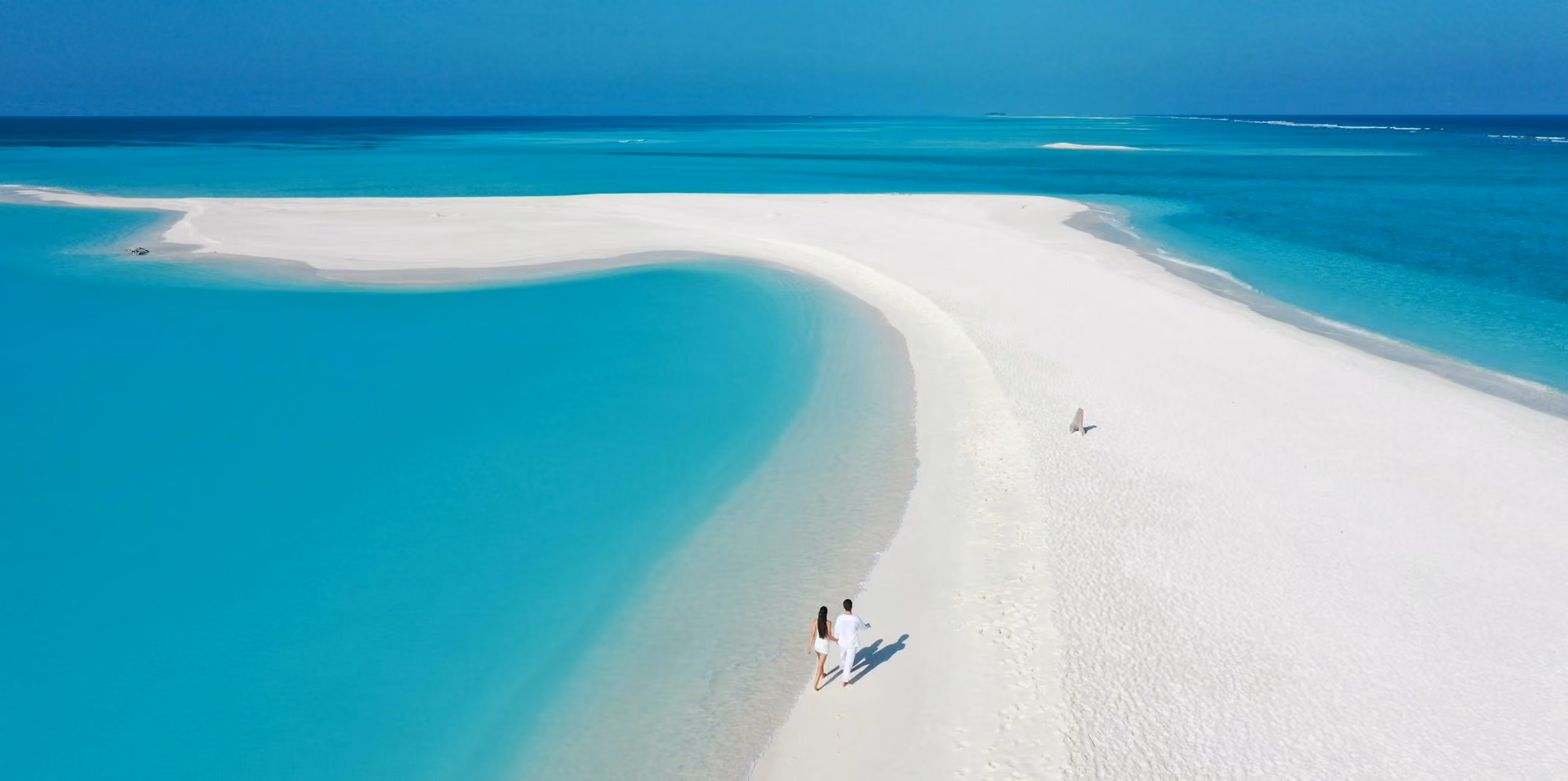 Near Soneva Fushi: Couple walking on a pristine white sandbar in turquoise water
