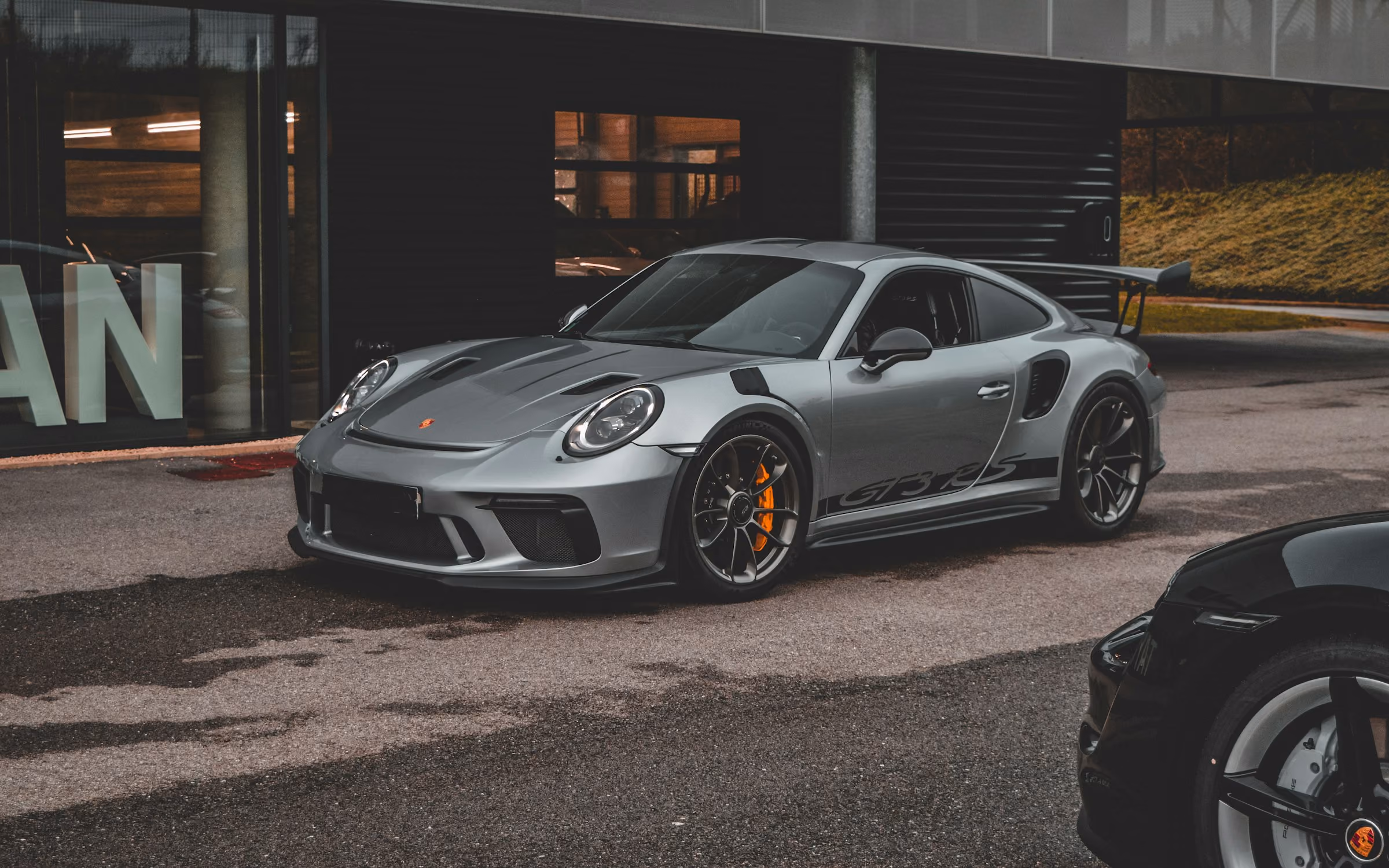 A grey Porsche 911 GT3 parked by a garage