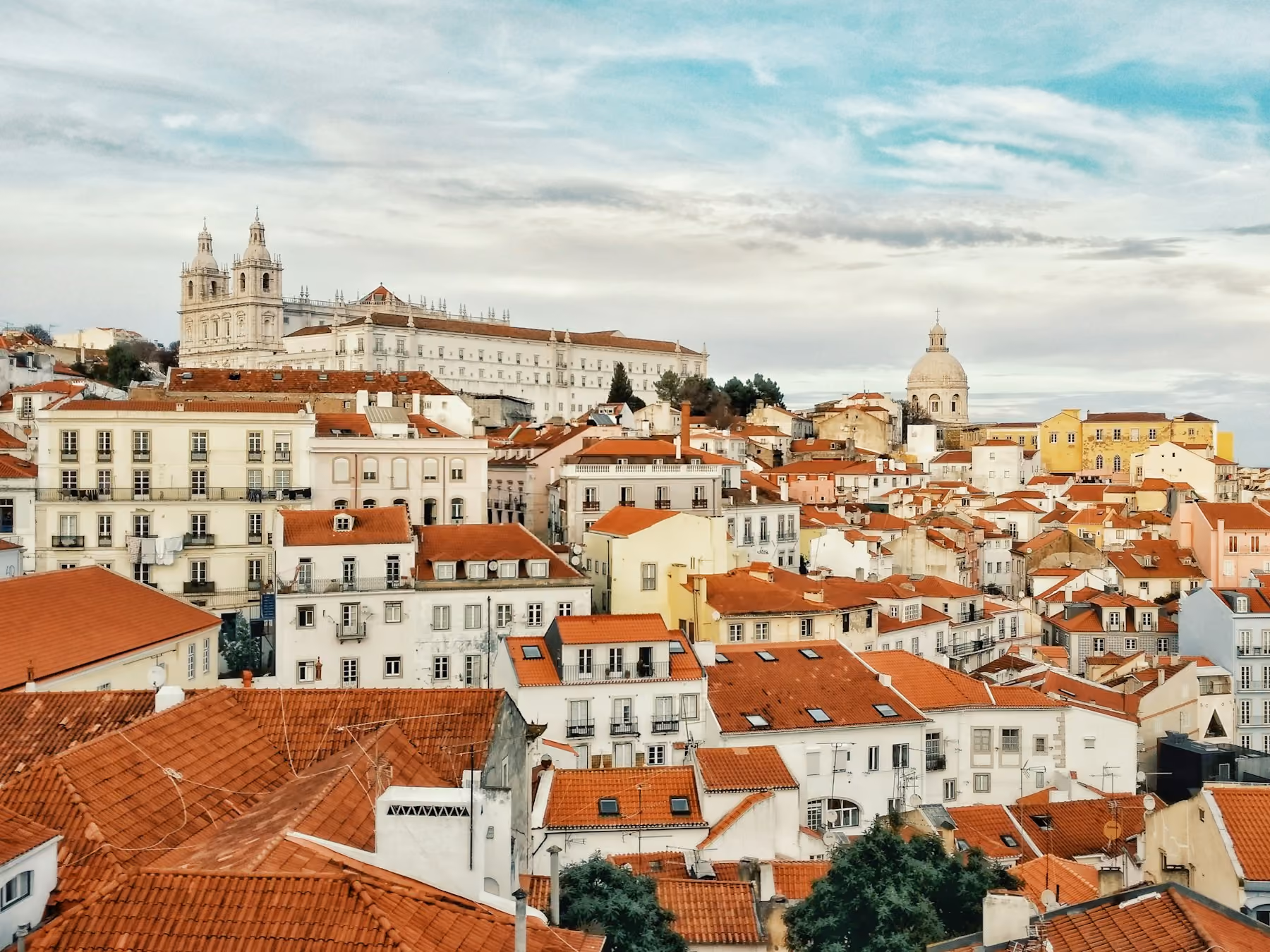 Terracotta rooftops of Alfama in Lisbon below the white dome of São Vicente de Fora