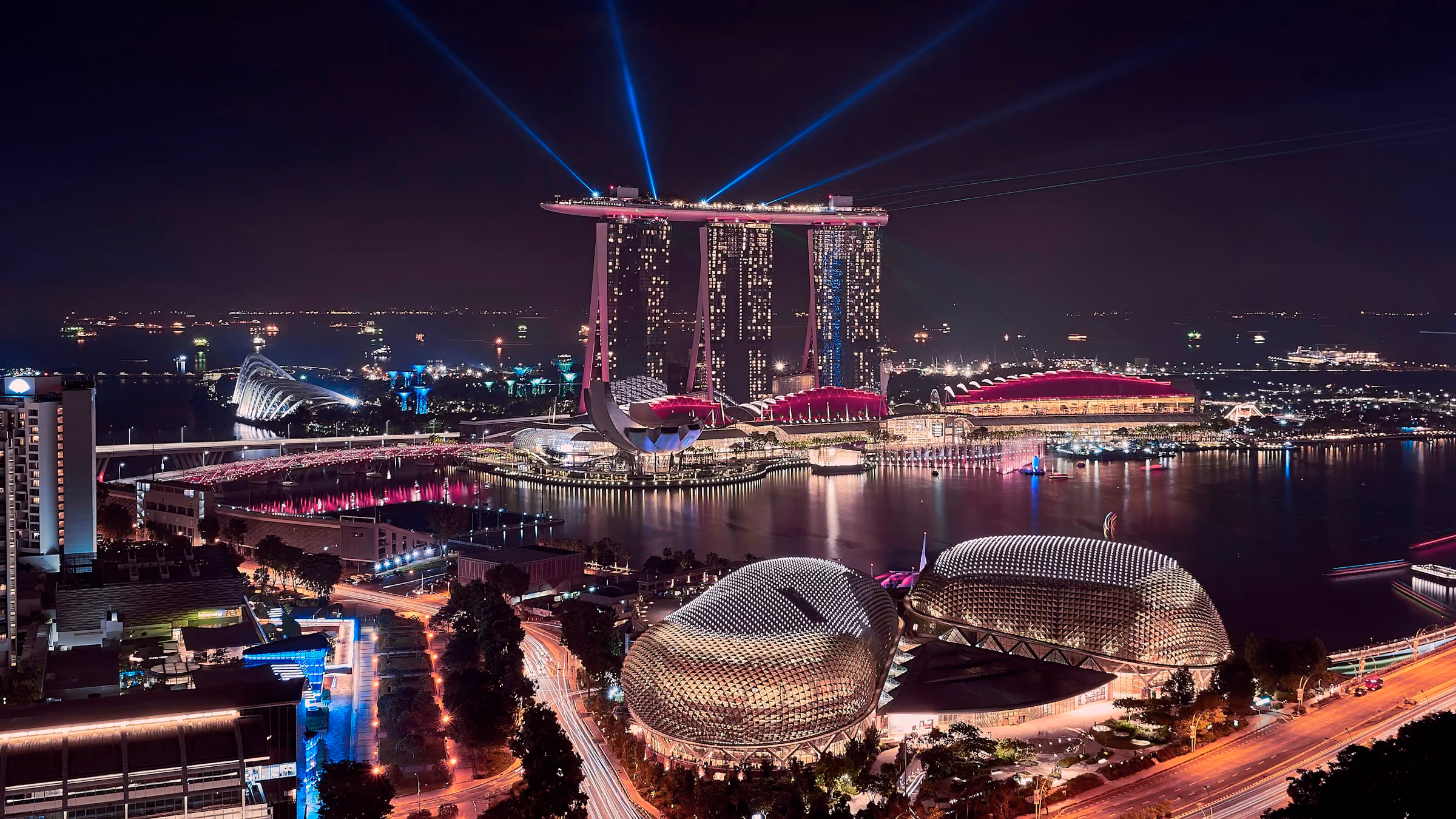 Singapore's Marina Bay lit up at night with searchlights in the sky
