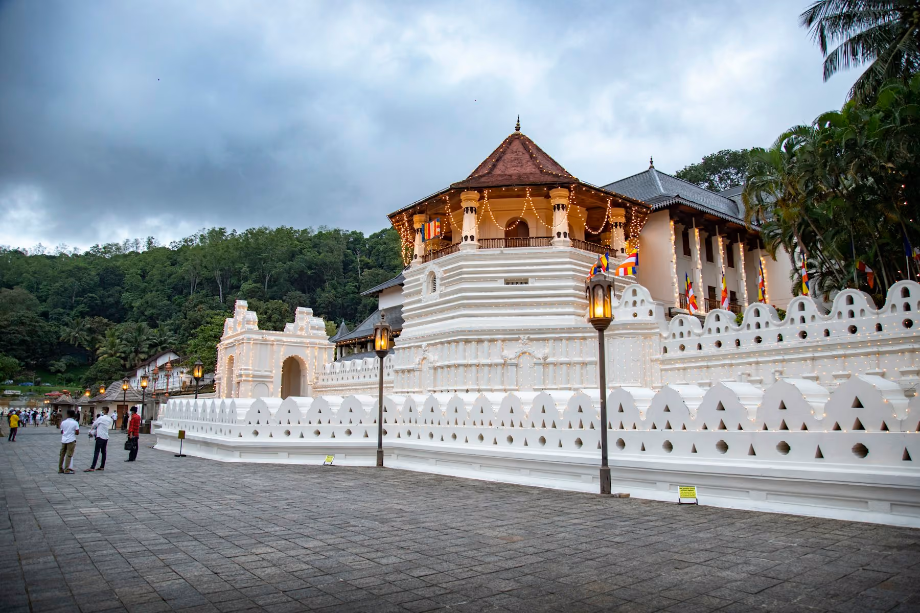 The Temple of the Tooth in Kandy, strung with lights and Buddhist flags at dusk