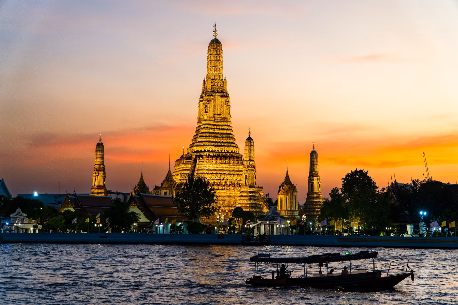 Wat Arun at sunset with a longtail boat on the Chao Phraya, Bangkok
