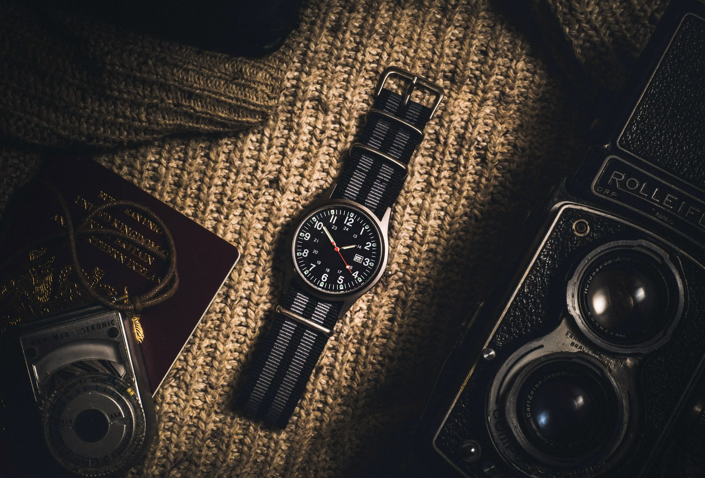 Watch insurance for travel: a watch laid out with a passport and a camera