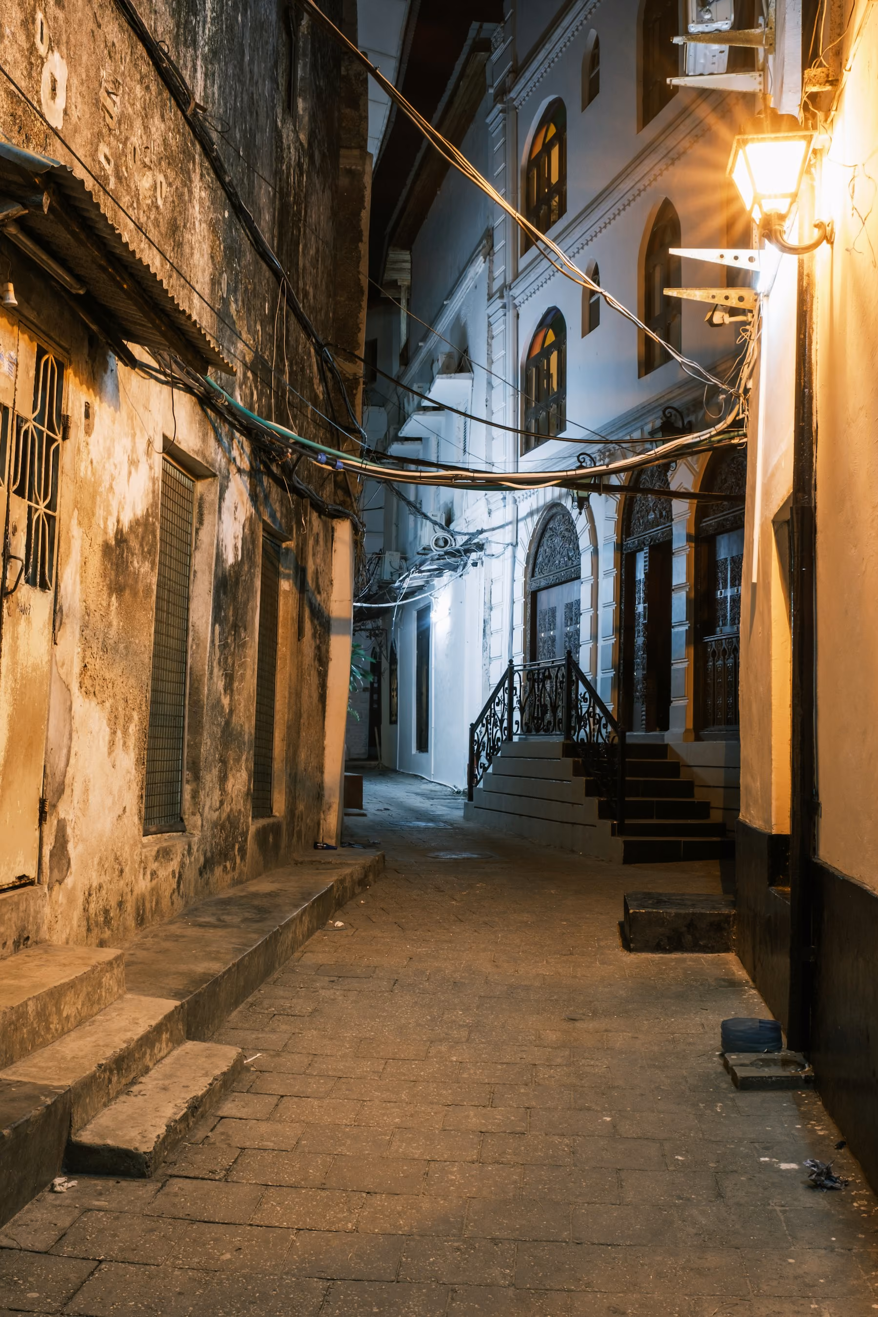 A narrow lamplit alley between coral stone houses in Stone Town, Zanzibar