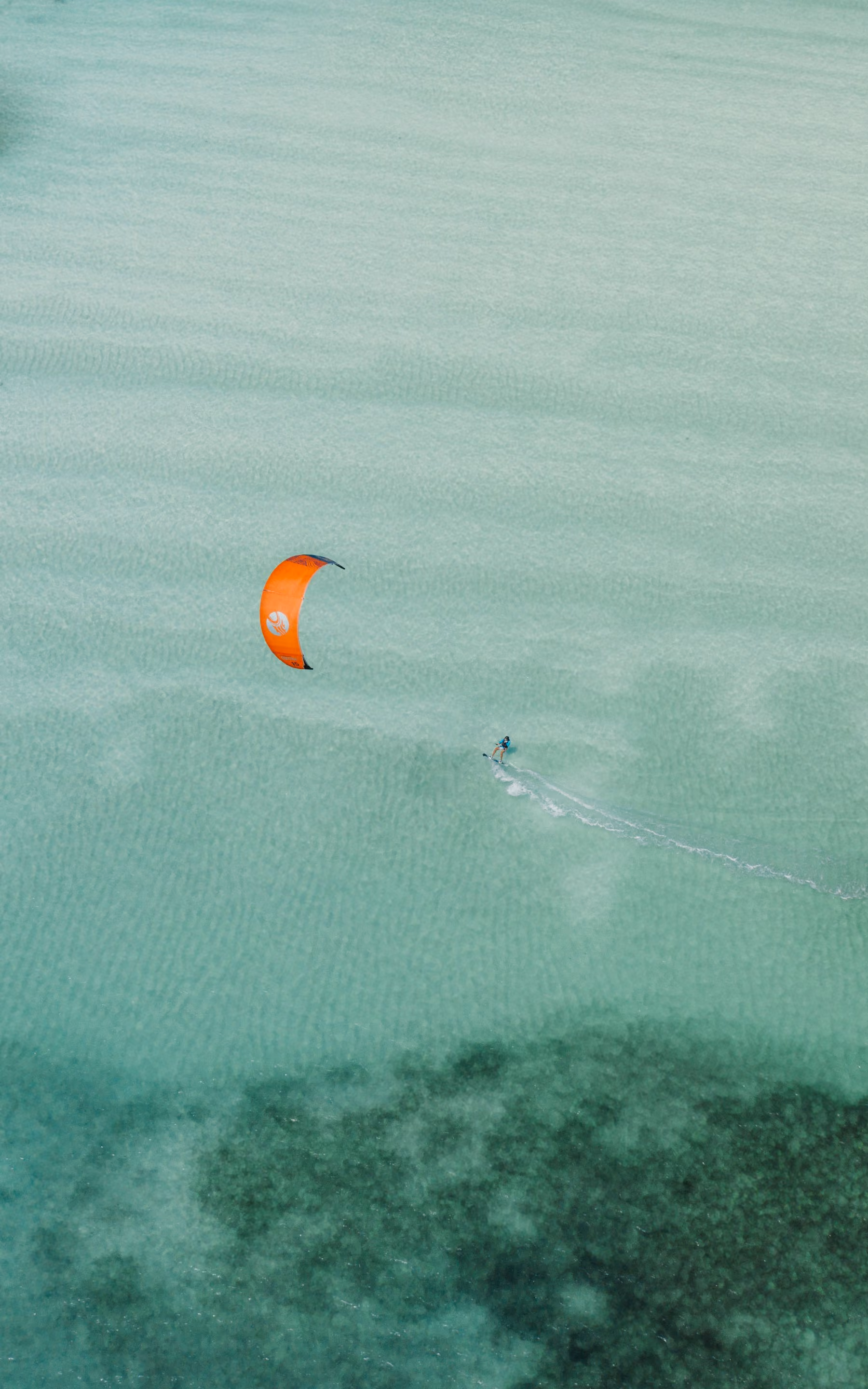 A kitesurfer on the turquoise lagoon at Paje, seen from above, in the Kusi wind season
